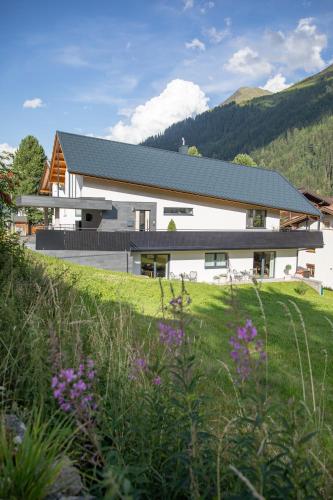 a white house with a grassy field in front of it at Starla 4 in Sankt Anton am Arlberg