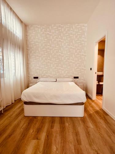 ein weißes Schlafzimmer mit einem Bett und Holzboden in der Unterkunft Apartamentos Sunsets Málaga Centro in Málaga