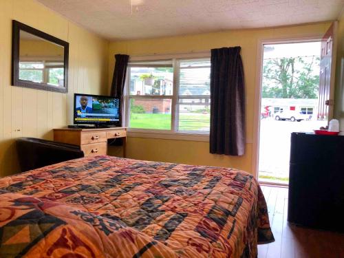 a bedroom with a bed and a television and a window at Lakelawn B&B and Motel in Yarmouth