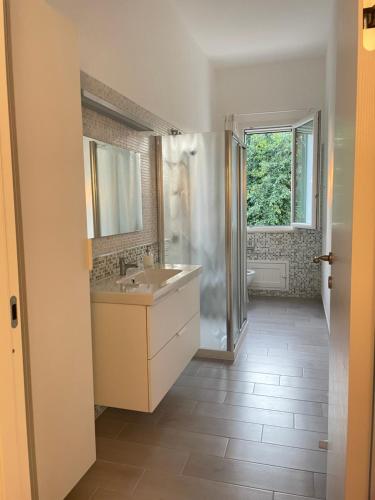 een badkamer met een wastafel, een spiegel en een raam bij La Casa di Dada in Terrasini