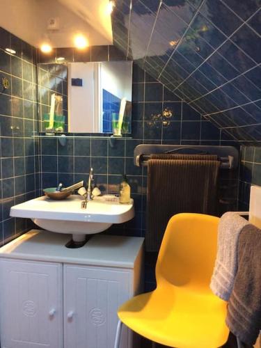 La salle de bains est pourvue d'un lavabo et d'une chaise jaune. dans l'établissement PLEIN CENTRE TRES GRAND STUDIO, à Trouville-sur-Mer