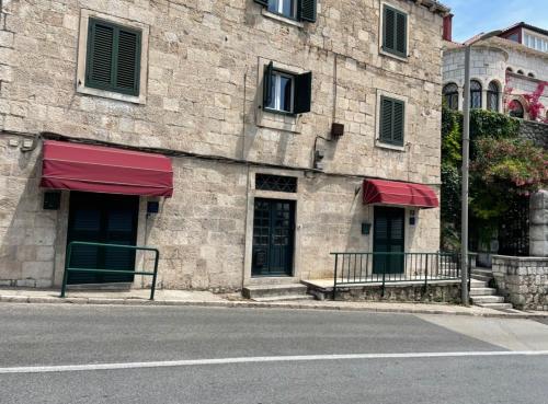 a building with red awnings on the side of a street at Jadranka studio apartments in Dubrovnik