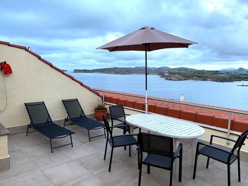 a patio with a table and chairs and an umbrella at Playa de los Locos con Garaje in Suances