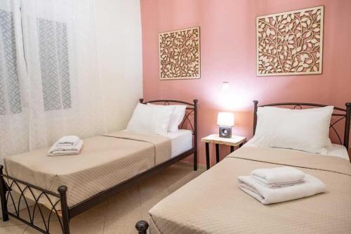 two beds in a room with pink walls at Marios house in Émbaros