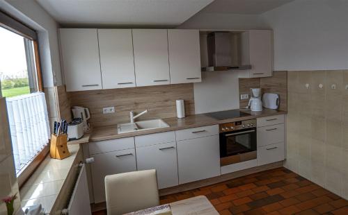a kitchen with white cabinets and a sink at Ferienwohnung Schleiblick in Maasholm