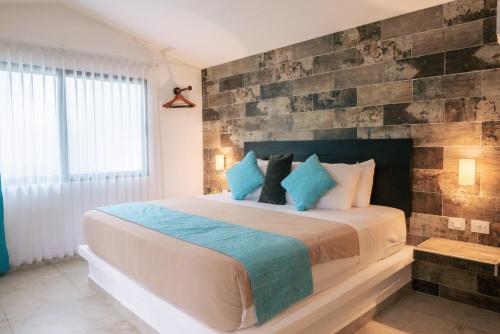 a bedroom with a large bed with a brick wall at Hotel Aldea 19 Bacalar in Bacalar