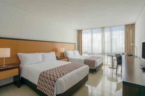 a hotel room with two beds and a desk at Estelar Alto Prado in Barranquilla