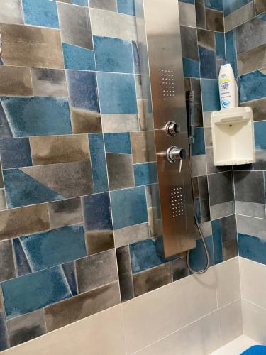 y baño con ducha de azulejos azules y marrones. en L'INCOGNITA, en San Nicolò dʼArcidano