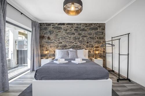 a bedroom with a large bed and a brick wall at Basalt House A by Homie in São Vicente