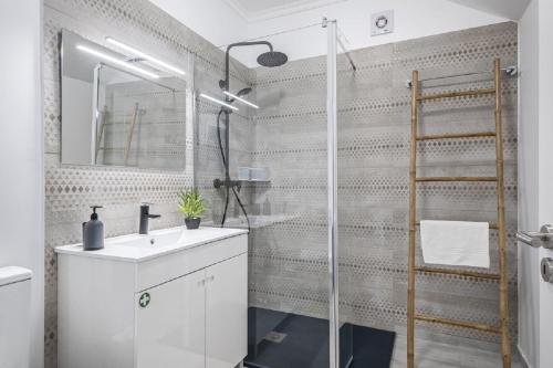 a bathroom with a shower with a sink and a mirror at Basalt House A by Homie in São Vicente