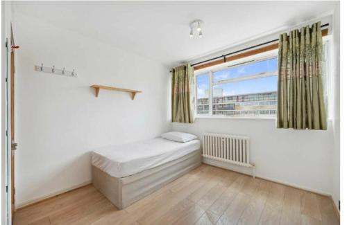 a small bedroom with a bed and a window at 3Bed Apartment Pimlico London in London