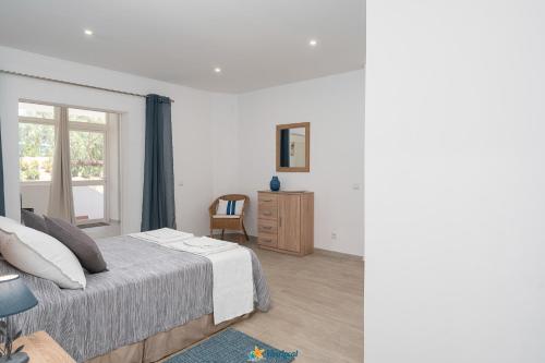 a white bedroom with a bed and a window at Quinta dos Arcos - Apartamento Viva Local in Alvor