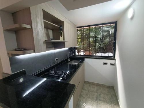 a kitchen with a black counter top and a window at Apartamento campestre LOFT con jacuzzi en San Lucas, El Poblado in Medellín