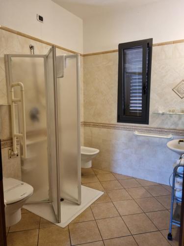 uma casa de banho com um chuveiro, um WC e uma janela. em Hotel Delle Isole em La Maddalena