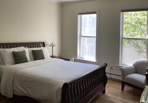 a bedroom with a bed and a chair and two windows at Lunenburg Arms Hotel in Lunenburg