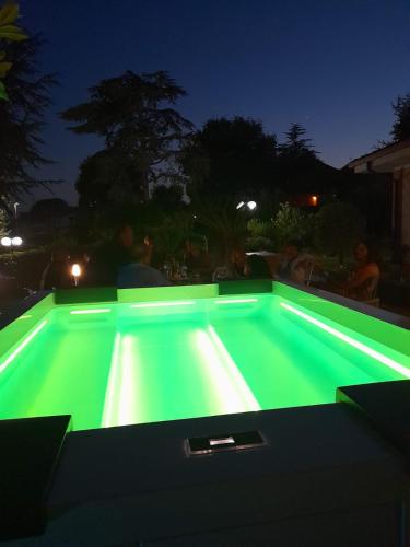 a swimming pool with green lighting at night at Il Sogno delle Rondini in Palidoro
