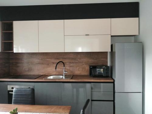 een keuken met witte kasten, een wastafel en een koelkast bij Apartman Sterpin in Pula