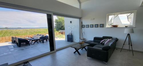 uma sala de estar com um sofá, uma mesa e uma porta de vidro em Robson Beach I Sauna, Jacuzzi em Międzywodzie