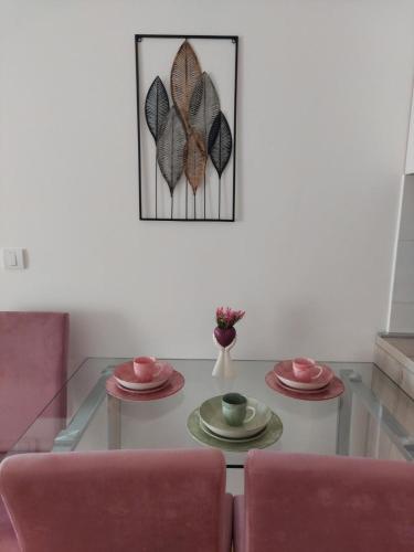 uma sala de estar com uma mesa de vidro com duas cadeiras cor-de-rosa em K2-SistersApartment em Podgorica