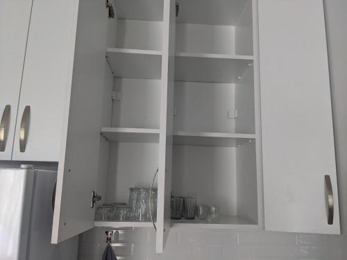 a white cabinet with empty shelves in a kitchen at Blue Apartment in Gonio