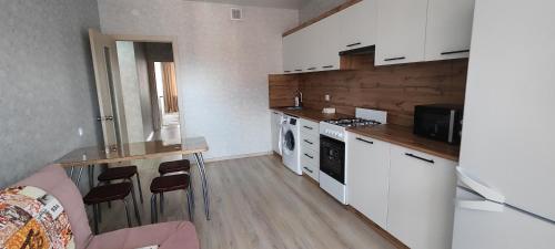 uma cozinha com armários brancos e uma bancada em Уютная 2 ком.квартира em Qostanay