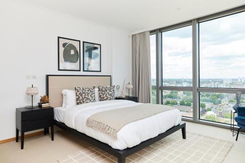 a bedroom with a large bed and large windows at The Canary Wharf Place - Stunning 2BDR Flat in London
