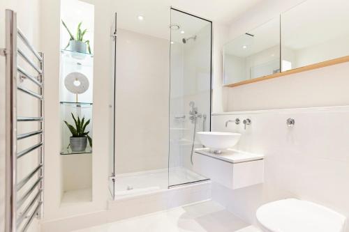 a white bathroom with a shower and a sink at The Canary Wharf Place - Stunning 2BDR Flat in London