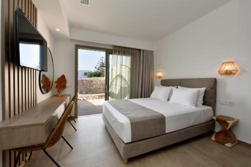 a bedroom with a bed and a desk and a television at Anais Milos Suites in Adamas