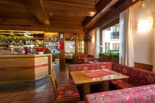 un restaurante con sillas rojas, una mesa y un bar en Hotel Garnì Ai Serrai, en Rocca Pietore