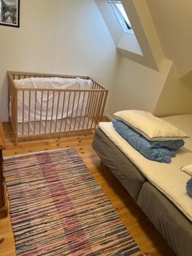 two beds in a room with a crib and a rug at Schou Lykke Nord in Tarm