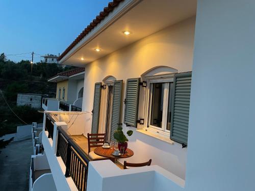 a balcony of a house with a table and windows at Loukas Apartments in Karavostamo