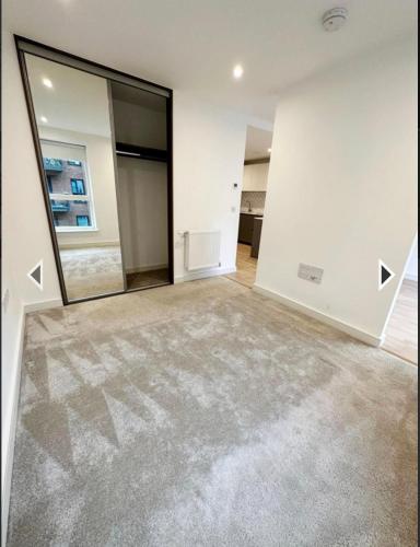 an empty living room with a large mirror at Studio flat greenleaf walk in Southall