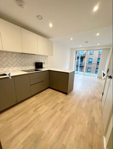 een lege keuken met witte kasten en een houten vloer bij Studio flat greenleaf walk in Southall