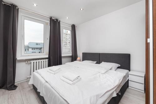 a bedroom with a bed with white sheets and a window at Apartamenty Pańska by Your Freedom in Warsaw