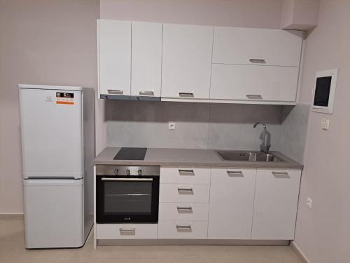 kuchnia z białymi szafkami, zlewem i lodówką w obiekcie Antigoni Apartment w mieście Suda