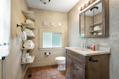 a bathroom with a sink and a toilet and a window at Stylish Cabin in Orick