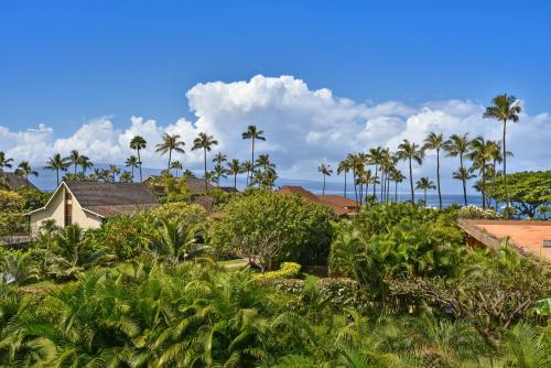 a garden with palm trees and a house at Maui Kaanapali Villas #A317 in Lahaina