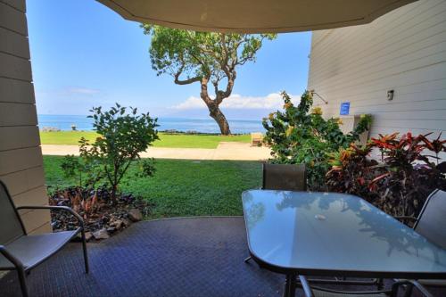 d'une terrasse avec une table, des chaises et un arbre. dans l'établissement Kahana Reef #116, à Kahana
