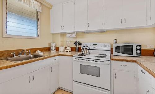 卡哈納的住宿－火娜科瓦伊精緻棕櫚＃A-7室公寓，厨房配有白色橱柜、炉灶和微波炉。