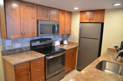 a kitchen with stainless steel appliances and wooden cabinets at Mahana Resort 612 in Kahana