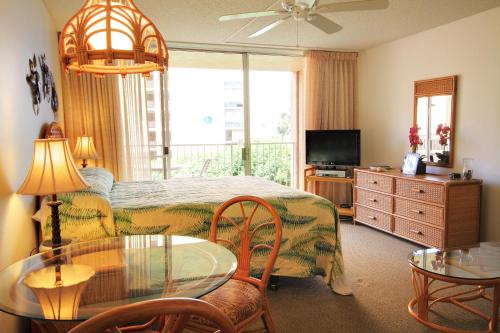 a bedroom with a bed and a table and a television at Royal Kahana #319 in Kahana