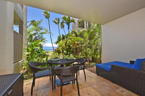 a patio with a table and chairs and the ocean at Hale Mahina #B102 in Kahana