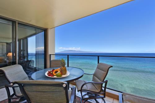 a table with a bowl of fruit on top of a balcony at Mahana Resort #1104 in Kahana