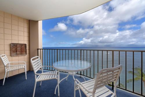 a balcony with a table and chairs and the ocean at Valley Isle #808 in Kahana