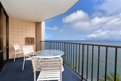 a balcony with a table and chairs and the ocean at Valley Isle #808 in Kahana
