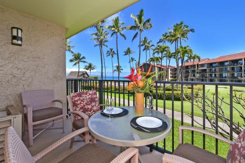 a balcony with a table and chairs and palm trees at Papakea #E207 in Kahana