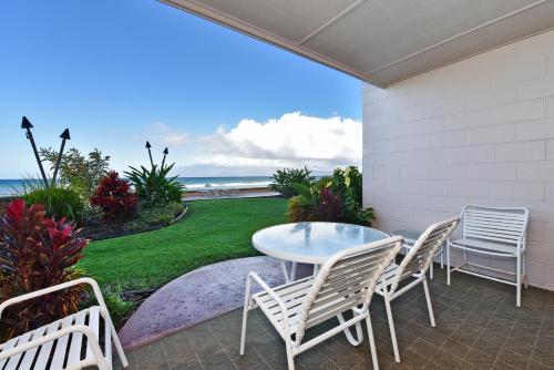 a patio with a table and chairs and the ocean at Makani Sands #102 in Kahana