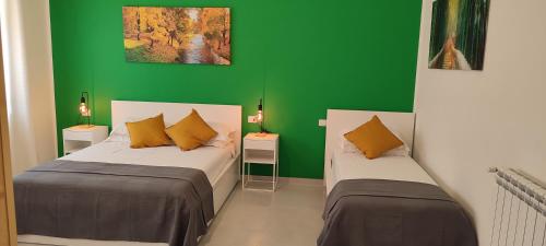 two beds in a room with a green wall at Manzoni 159 in Naples
