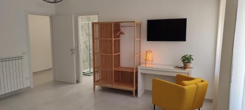 ein Wohnzimmer mit einem TV und einem gelben Stuhl in der Unterkunft Manzoni 159 in Neapel