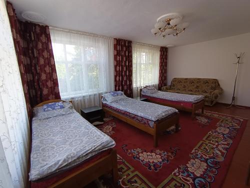 uma sala de estar com duas camas e um sofá em Meerim Guest House em Bokonbayevo